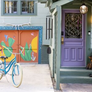 Welcoming entrance with purple door and cruiser bikes parked in the driveway.