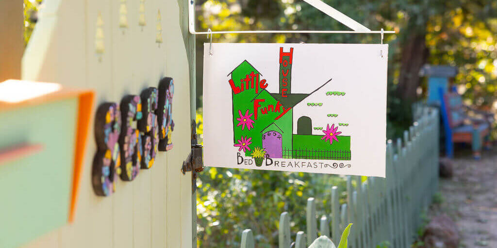 Sign for Little Funky House hanging by the street
